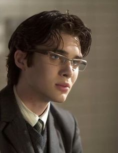 a young man wearing glasses and a suit