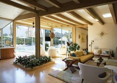 a living room filled with furniture and lots of windows next to a swimming pool on top of a wooden floor