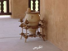 a large white vase sitting on top of a wooden stand in front of a wall