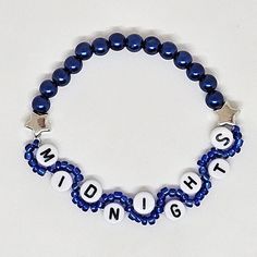 a blue beaded bracelet with white letters and stars on the clasp that says midnight