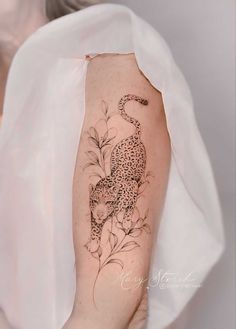 a woman's arm with a tattoo on it that has a leopard and flowers