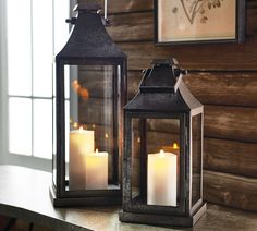 two lanterns sitting on top of a table next to each other with lit candles in them