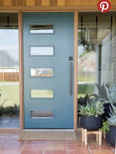 a blue front door with two planters on the side and one potted plant next to it