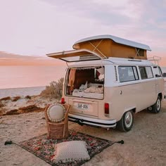 an old vw van parked on the beach with its roof open and it's bed pulled up