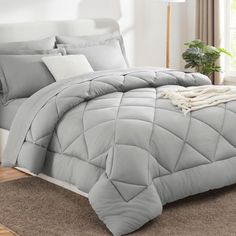 a bed with grey comforter and pillows in a room