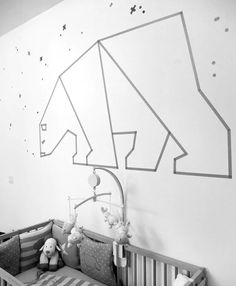 a black and white photo of a baby's room with an origami horse on the wall