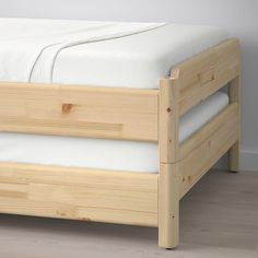 a wooden bed frame with white sheets and pillows