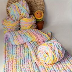 a crocheted blanket and two balls of yarn next to a potted plant