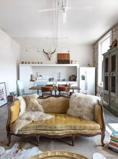 a living room filled with furniture next to a table and bookshelf on top of a hard wood floor