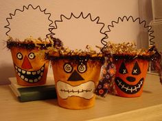 three decorated pots sitting on top of a wooden table