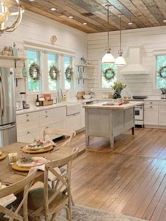 a kitchen with wooden floors and white walls, decorated for the holiday season by wreaths hanging on the ceiling