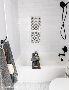 a white bathroom with black and white accessories on the bathtub, toilet and shower head