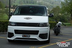 a white van parked in a parking lot next to a motorcycle