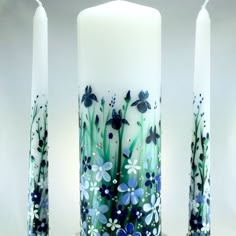 two candles with flowers painted on them sitting next to each other