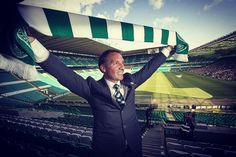 a man in a suit and tie holding up a green and white scarf over his head