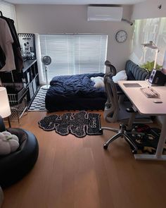 a bedroom with a bed, desk and chair in it's center area next to a window