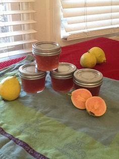 several jars of honey sit on a table with lemons