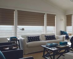 a living room filled with furniture and windows covered in roman blind shades on top of them