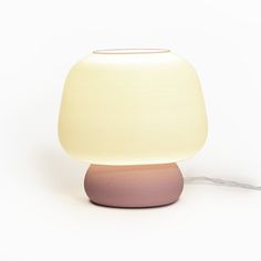 a white and pink lamp sitting on top of a table next to a light bulb