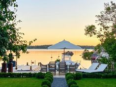 an outdoor dining area with chairs and umbrellas on the water's edge at sunset