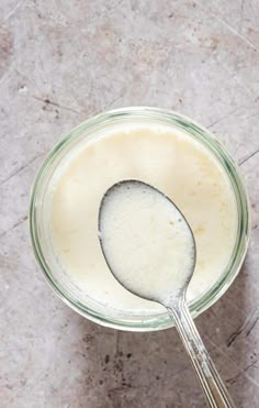 a spoon is in a glass bowl filled with milk on the floor next to a marble surface