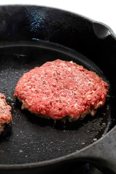 two hamburger patties cooking in a frying pan