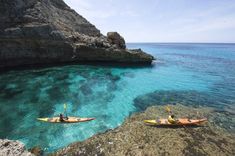 two people are kayaking in clear blue water