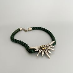 Beautiful vintage Bavarian Edelweiss flower necklace.  Emerald green braided silk cord and metal.  Edelweiss is a favorite motif in Bavarian women's jewelry for a dirndl (Bavarian traditional dress) or costume. ⚜️Good vintage condition with traces of use.  But that's exactly what separates vintage treasures from modern pieces ⚜️More Bavarian vintage: https://www.etsy.com/de/shop/JDVintageDE ⚜️Dimensions: Necklace : 43 cm  Edelweiss : 7.5 cm x 4 cm  Extension chain : 5.5 cm  ⚜️Shipment :  from Ge Folklore Jewelry, Edelweiss Necklace, Edelweiss Jewelry, Edelweiss Flower, Necklace Emerald, Costume Necklaces, Silk Cord, Traditional Dress, Jewelry For Women