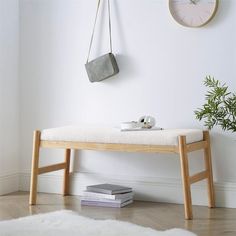 a wooden bench sitting next to a wall with a clock on it's side