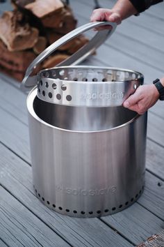 a person holding a large pot on top of a wooden deck