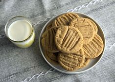 a plate of cookies next to a glass of milk on a tablecloth with a cloth