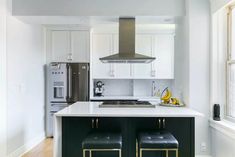 a kitchen with two stools next to an island