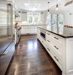 a large kitchen with white cabinets and wood floors