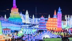 people are standing around in front of an illuminated cityscape with buildings and lights on it