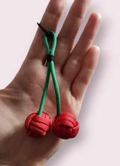 a hand holding two red and green knotted balls