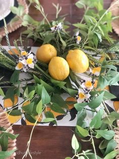 three lemons are sitting on top of some green leaves and flowers in the center