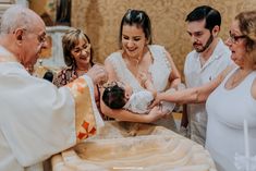 a group of people standing around a baby being held by an older man and woman