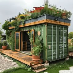 a green shipping container with plants growing on top and stairs leading up to the roof