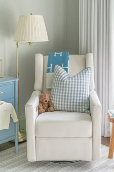 a teddy bear is sitting on a chair in the corner of a room with blue and white furniture