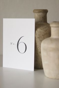 a white card with the number six on it next to two vases