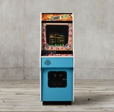 an old fashioned arcade machine sitting on top of a wooden floor next to a wall