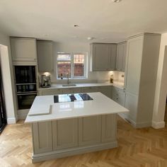 a large kitchen with an island in the middle and wooden flooring on the other side