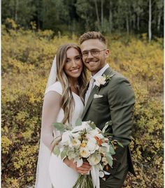 a bride and groom pose for a photo in front of the woods on their wedding day