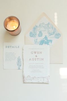 the wedding stationery is laid out next to a candle and some other things on the table