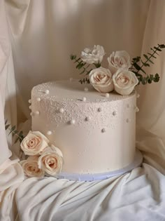 there is a wedding cake with white flowers on the top and pearls on the bottom