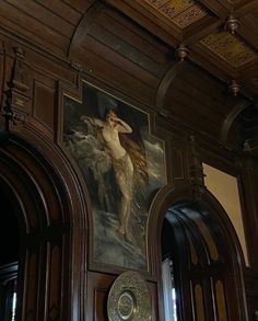 a painting on the wall above a door in a room with wood paneling and ornate doorways