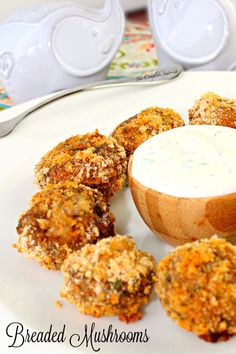 a white plate topped with fried food and a bowl of ranch dressing next to it