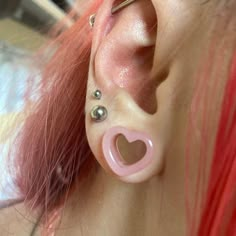 a woman with pink hair has two piercings on her ear and is wearing a heart shaped nose ring