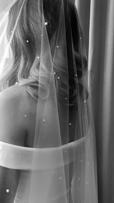 black and white photograph of a woman wearing a wedding veil with pearls on the side