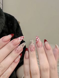 two hands with red and white nail designs on them